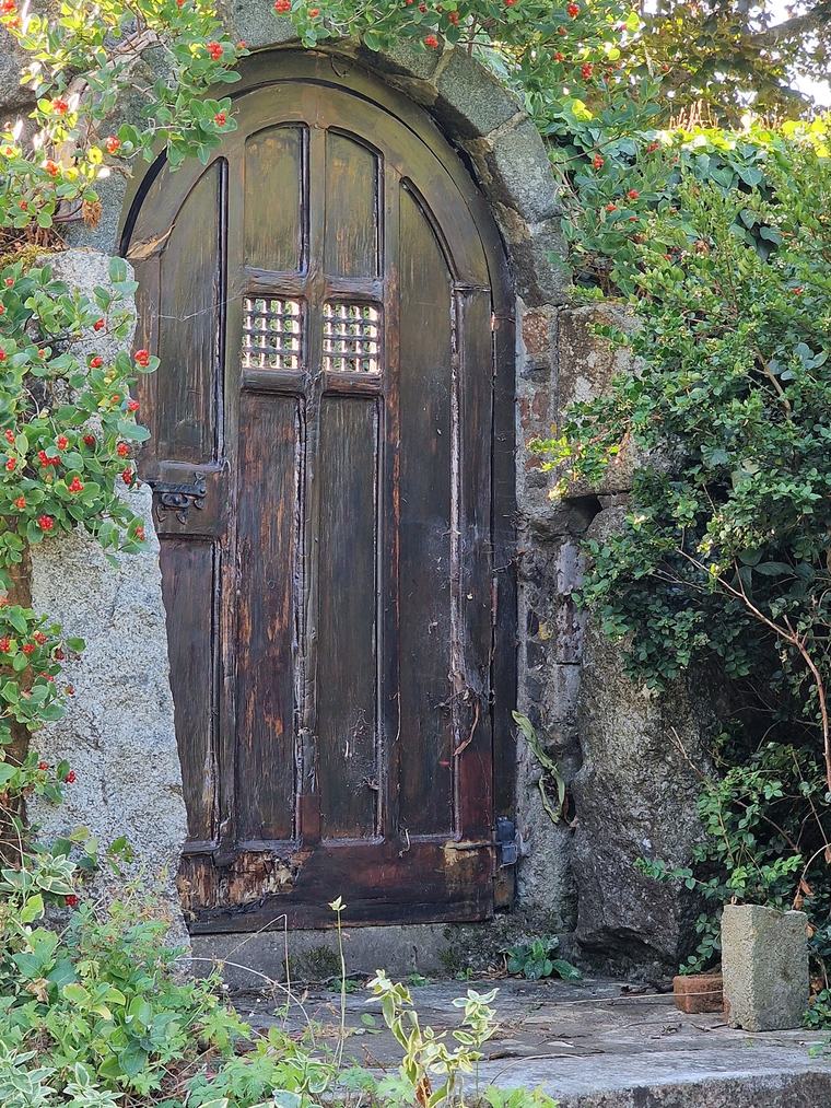 Weathered arched oak door before restoration by Le Foulon Joinery, showing rot to the bottom rail and damaged lattice grilles