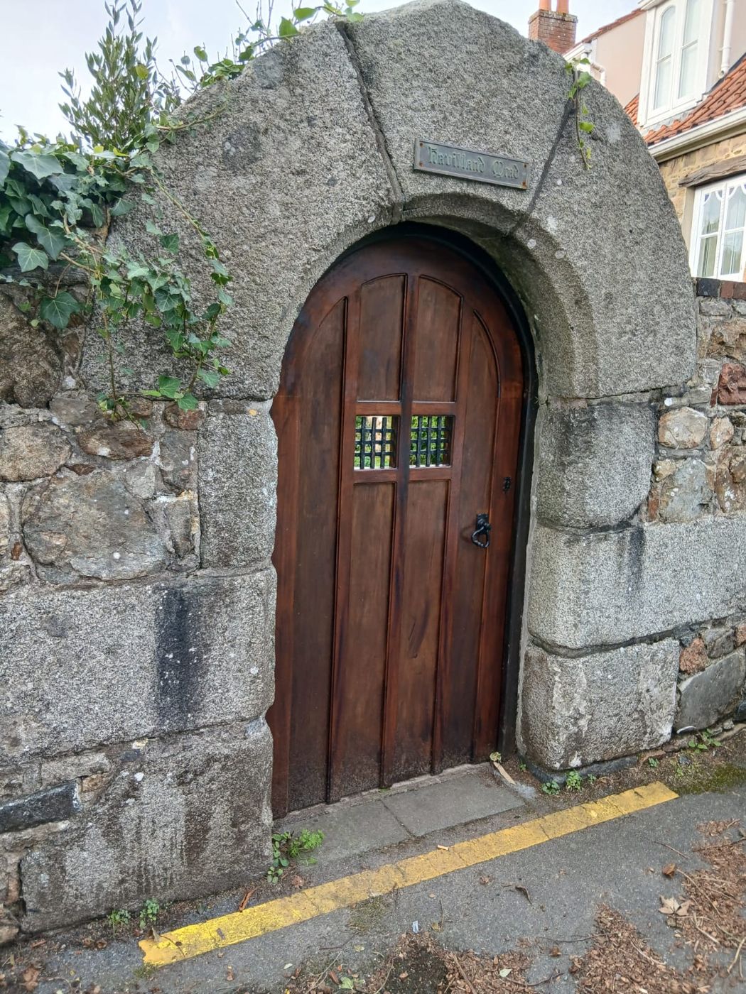 Finished arched door restored by Le Foulon Joinery, seen from the street in its granite wall
