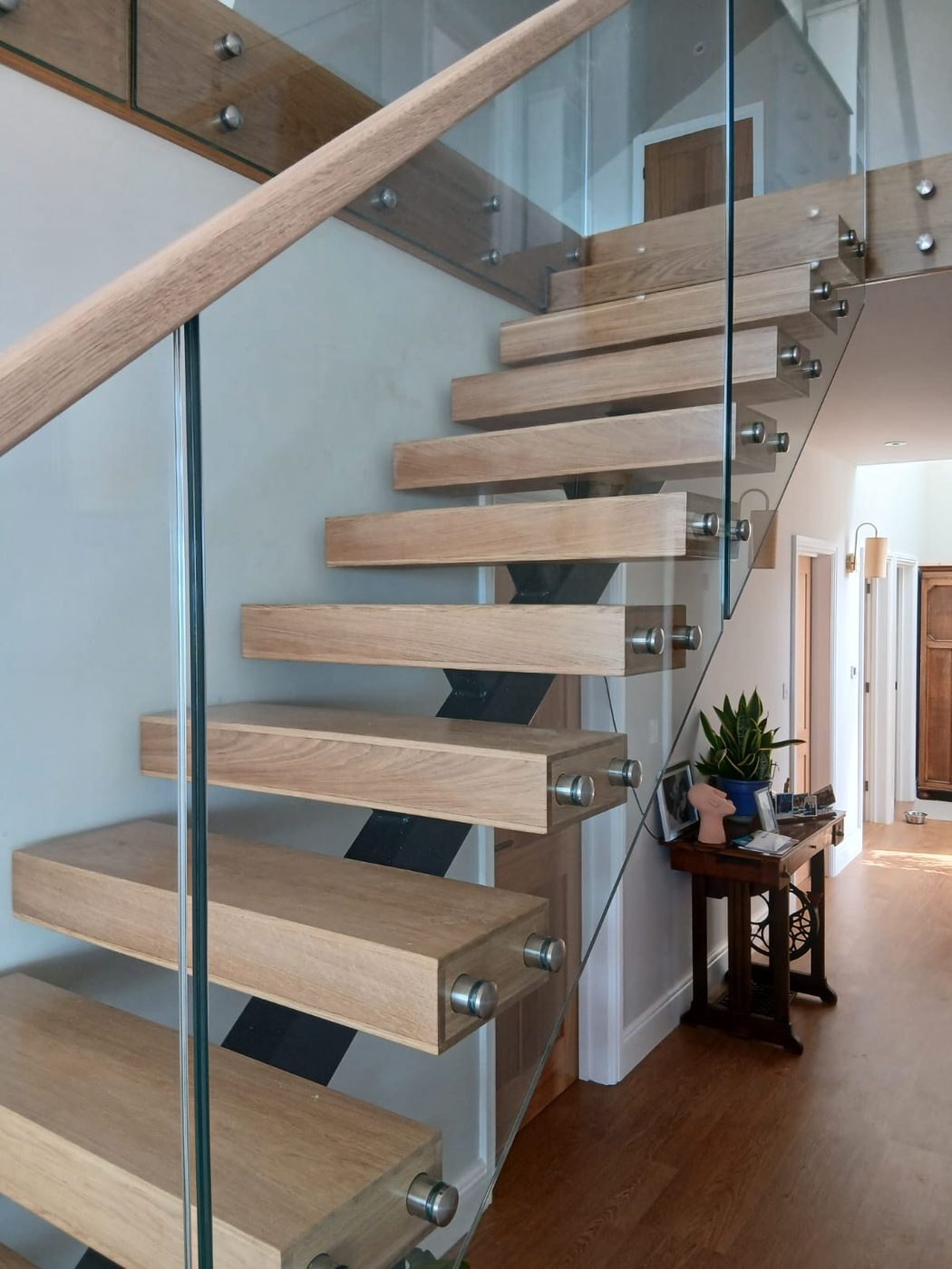 Floating oak staircase with glass balustrade and oak handrail, made and fitted by Le Foulon Joinery in a Guernsey home